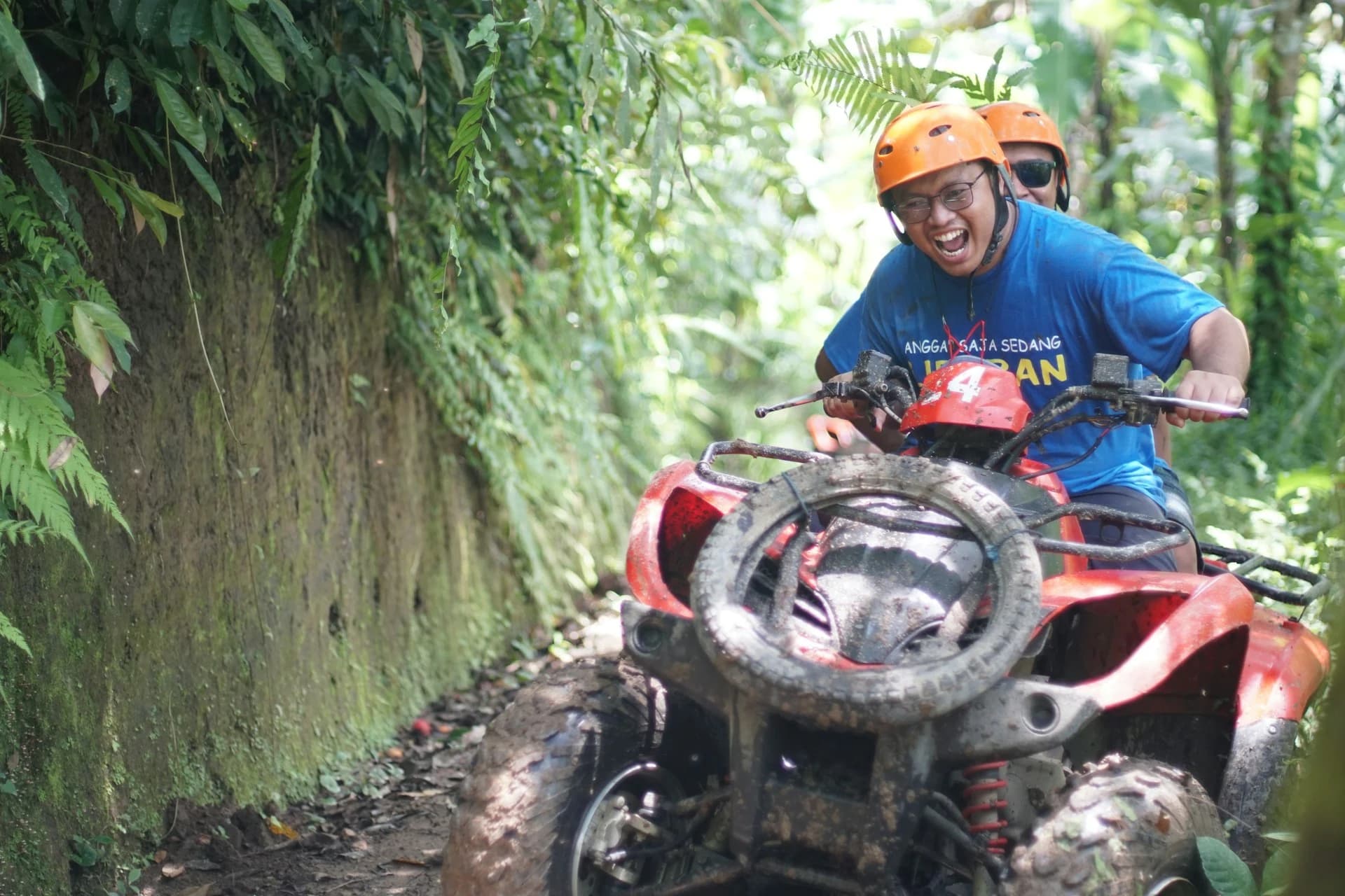 Riders on quad bikes on a dusty jungle trail below the white Big Buddha statue in Phuket