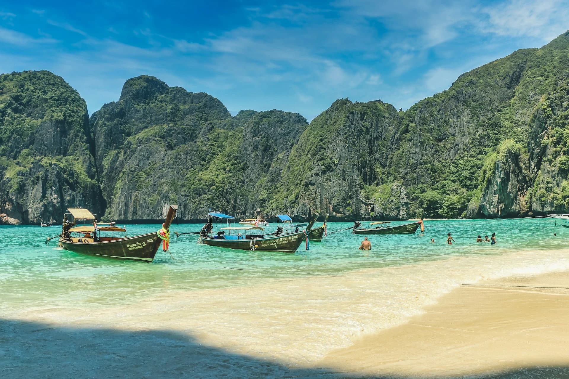 Speedboat anchored in turquoise water below the limestone cliffs of Phi Phi Leh on a day tour from Phuket