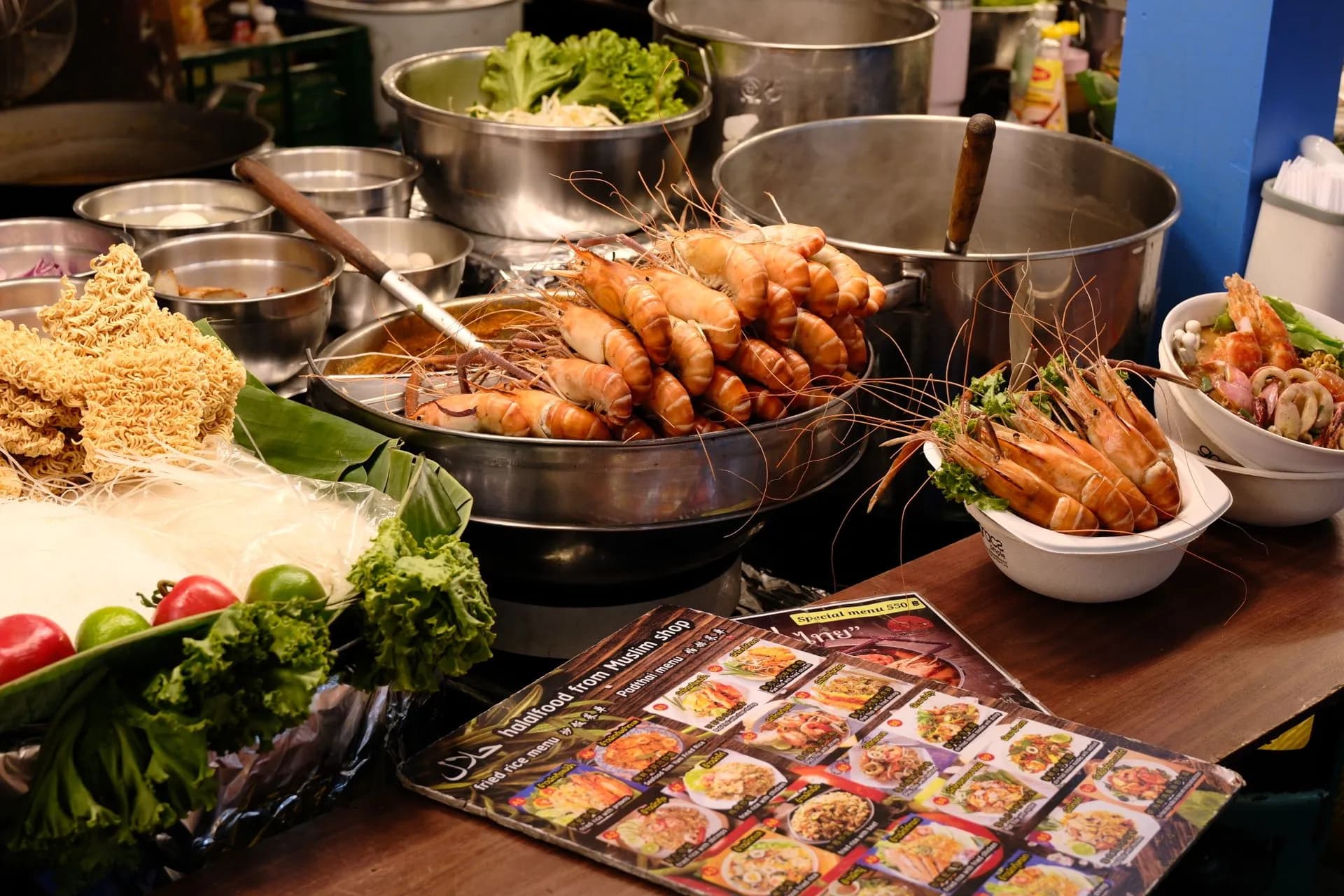 Bowls of Hokkien noodles and roti on a shophouse table along a pastel Phuket Old Town street