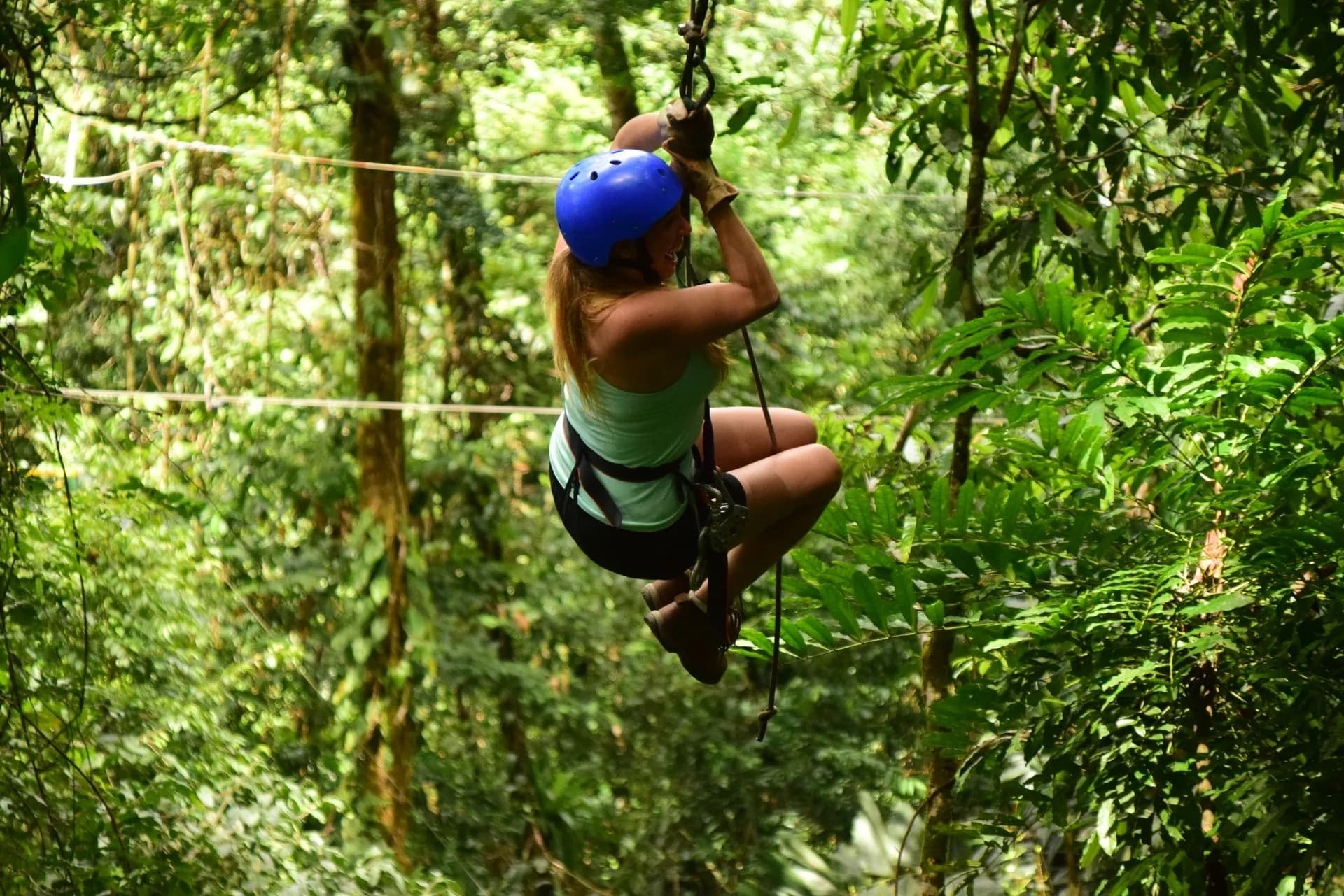 Rider on a jungle zipline between treetop platforms in the rainforest hills of Phuket, Thailand